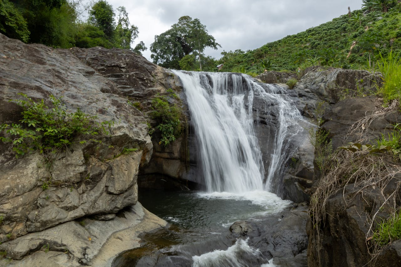 A tranquil waterfall cascading over rocks in a lush outdoor setting.