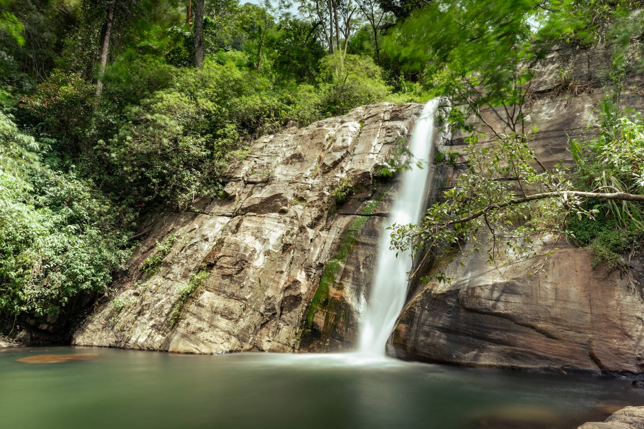 Beautiful waterfall cascading down a rocky cliff surrounded by lush greenery in Sri Lanka.